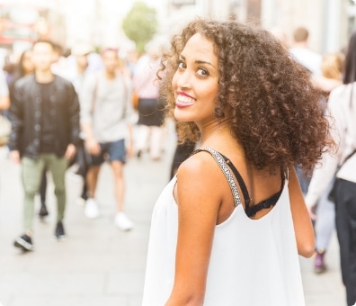 Women turning over her left shoulder smiling in a crowded street