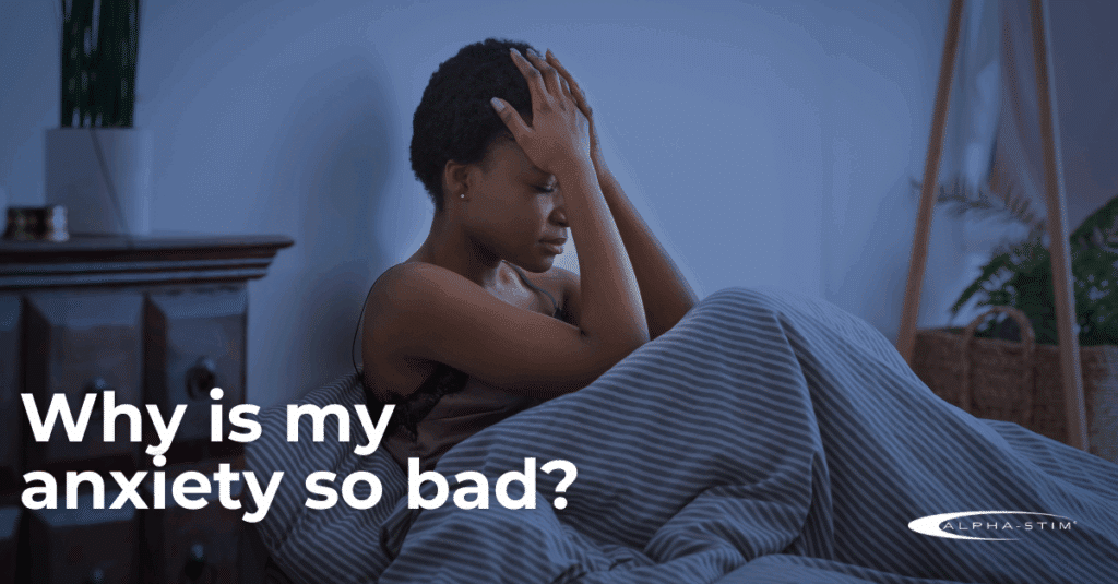 A woman sits in bed with her head in her hands, looking stressed. Text reads, Why are my anxiety symptoms so bad?.